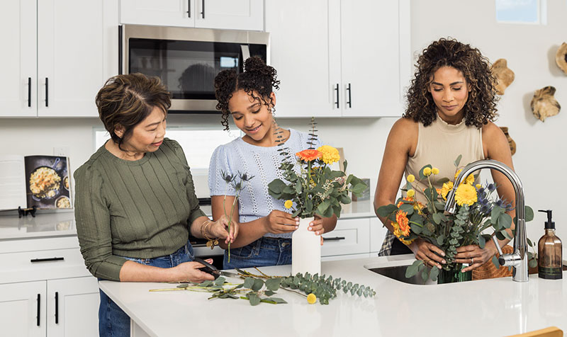 Image of family in kitchen arranging flowers.